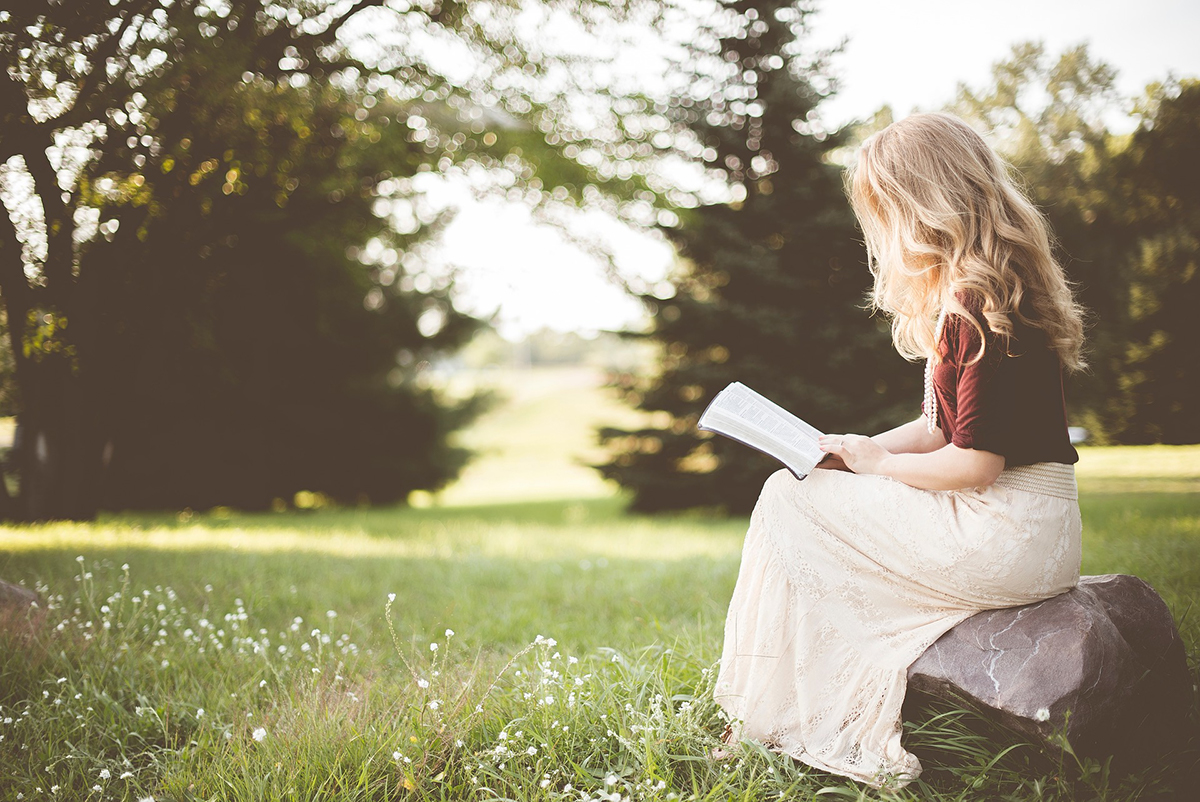 Mujer leyendo libro tranquila en medio de la naturaleza